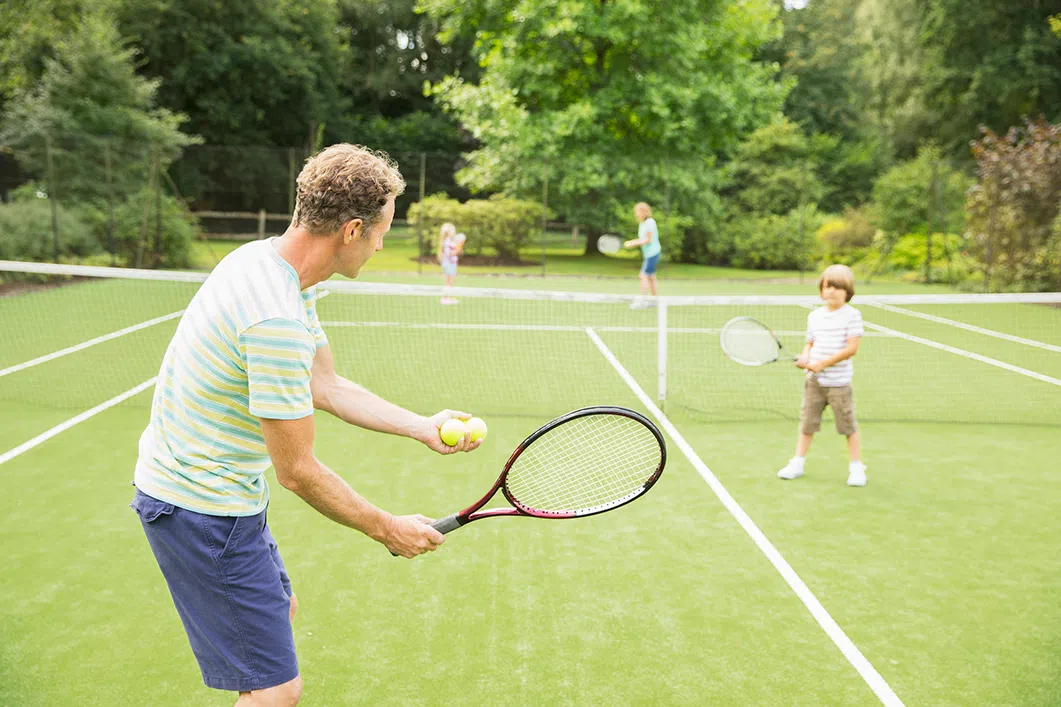 Family playing tennis on grass court image