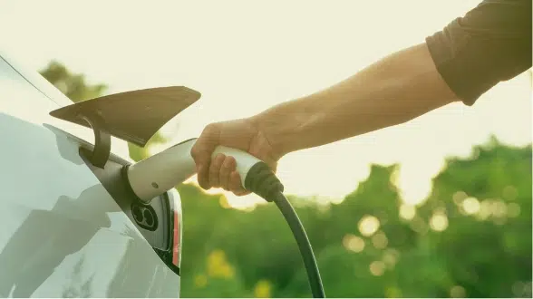 person plugging in EV charger to car image