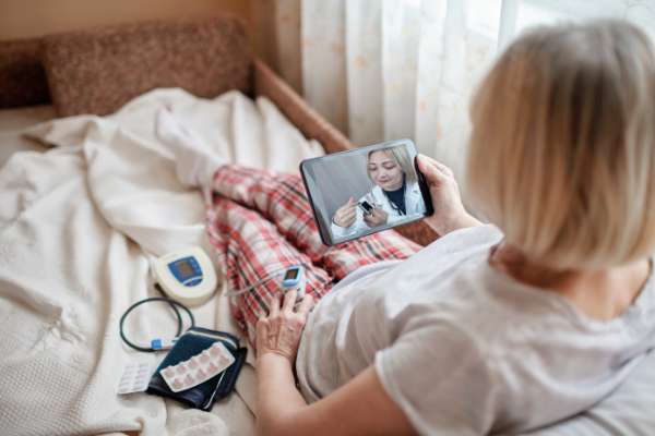 lady in bed on tablet to healthcare worker image