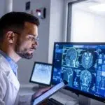 doctor on tablet with pc monitor checking scans image