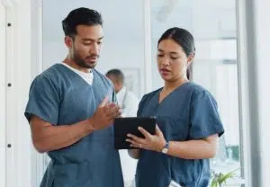 Zwei Mitarbeiter des Gesundheitswesens betrachten ein Tablet-Bild.