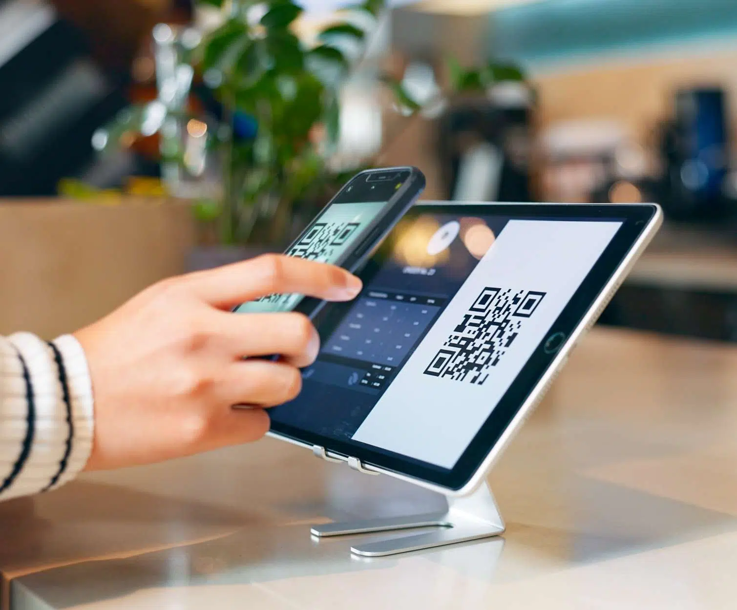 person in retail scanning QR code with mobile phone onto tablet image