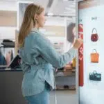 woman in shop on touch screen monitor in store image