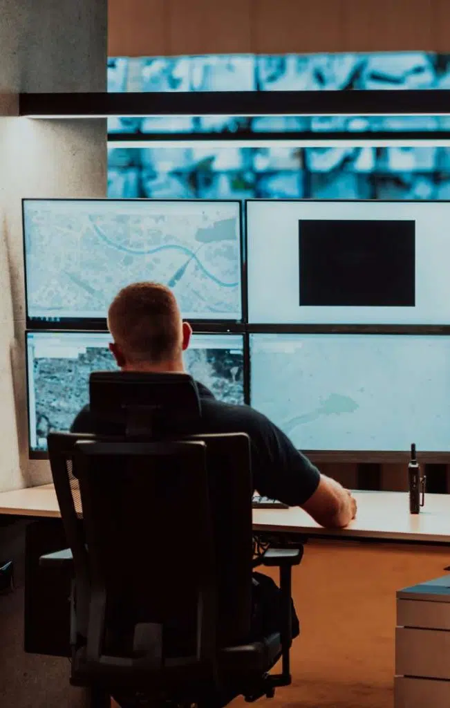 man at desk with multiple screens monitoring image