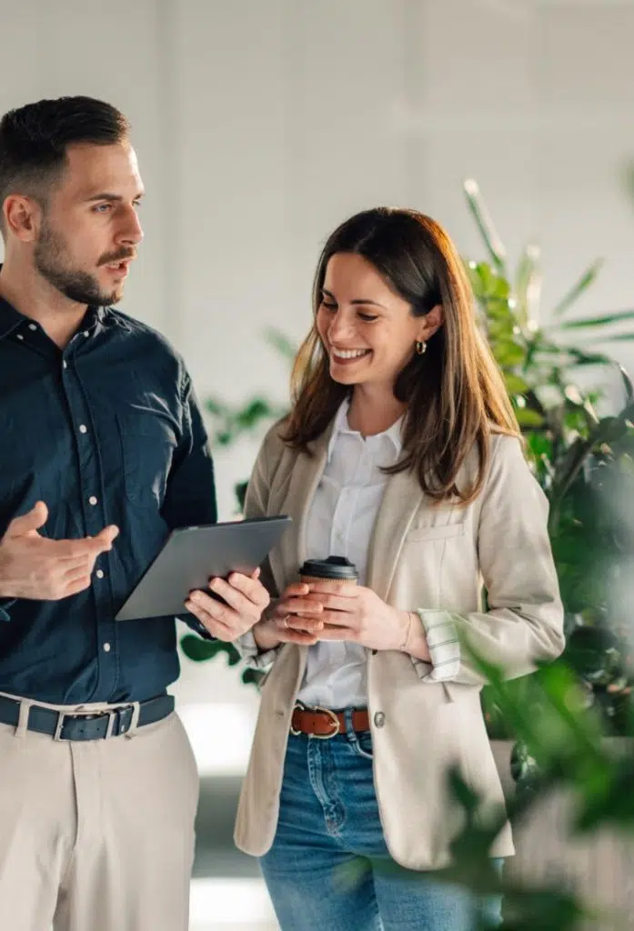 Mann hält Tablet, spricht mit Frau, die Kaffee hält Bild