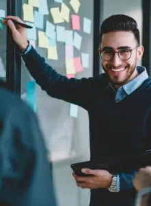 Mann lächelt und schreibt auf eine Tafel