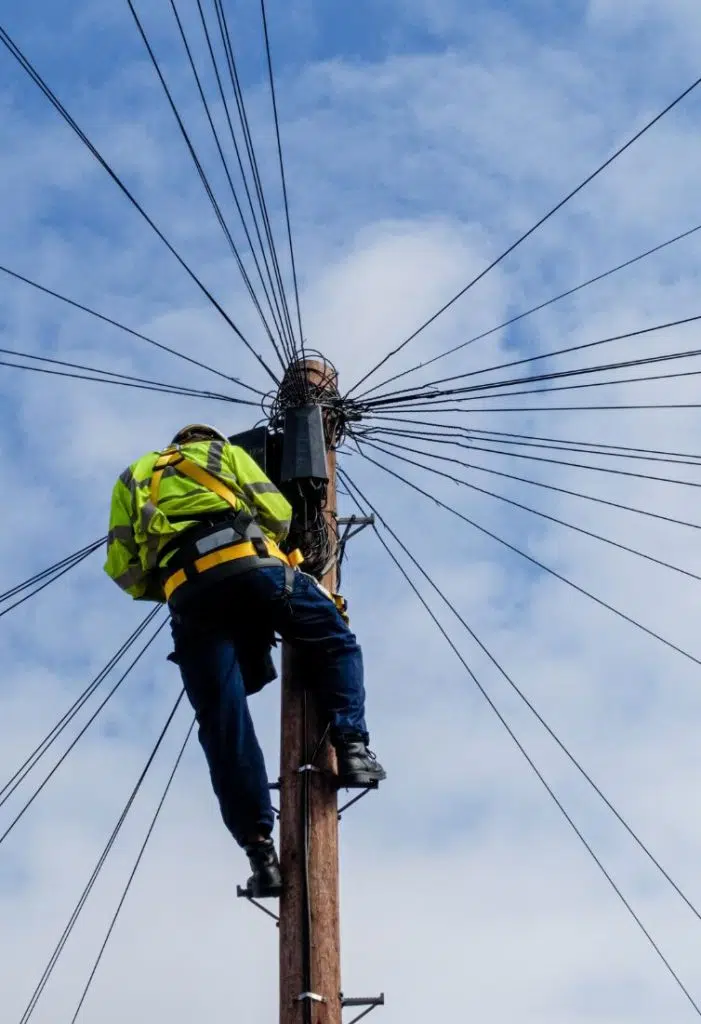 man in high-vis at top of telephone pole with cables image