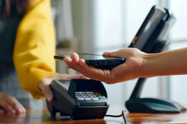 person paying on pin machine in shop with smart phone image