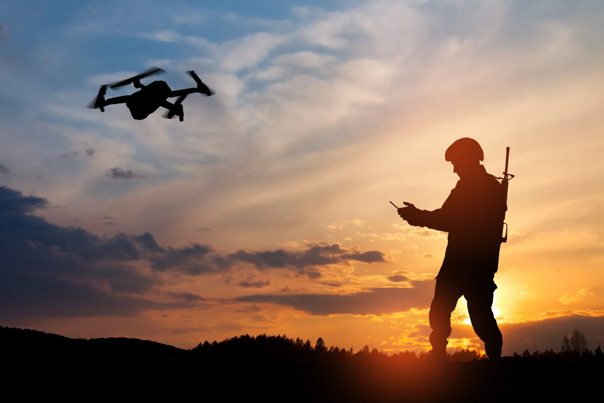 Silhouette of soldier are using drone and laptop computer in sunset.